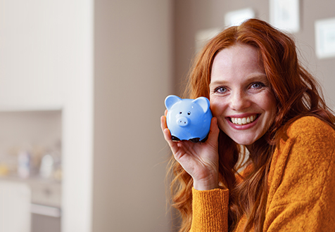 Frau mit blauem Sparschwein in der Hand