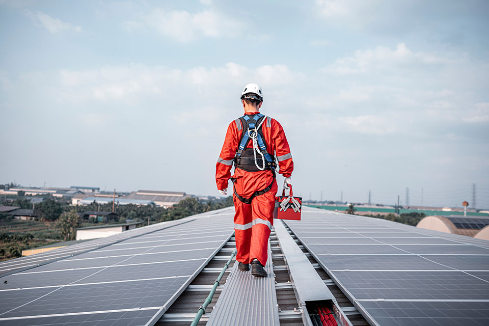 Techniker in Schutzkleidung geht auf Solarpanels