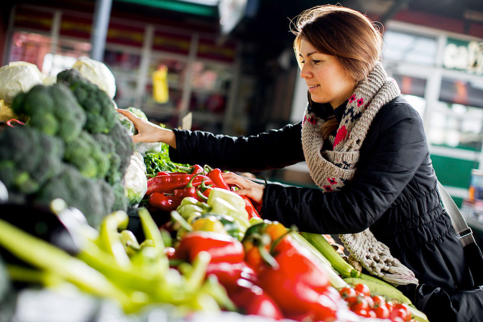 Foto einer jungen Frau, die Gemüse auf dem Markt kauft (Foto: boggy22/istockphoto.com)