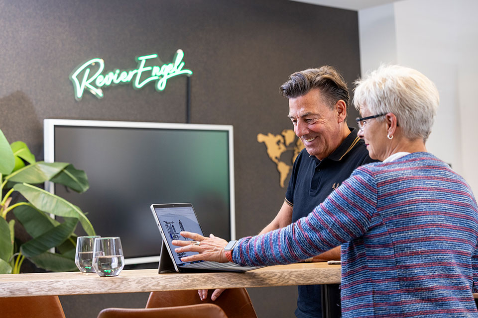 Zwei Personen betrachten Tablet an Tisch im Büro