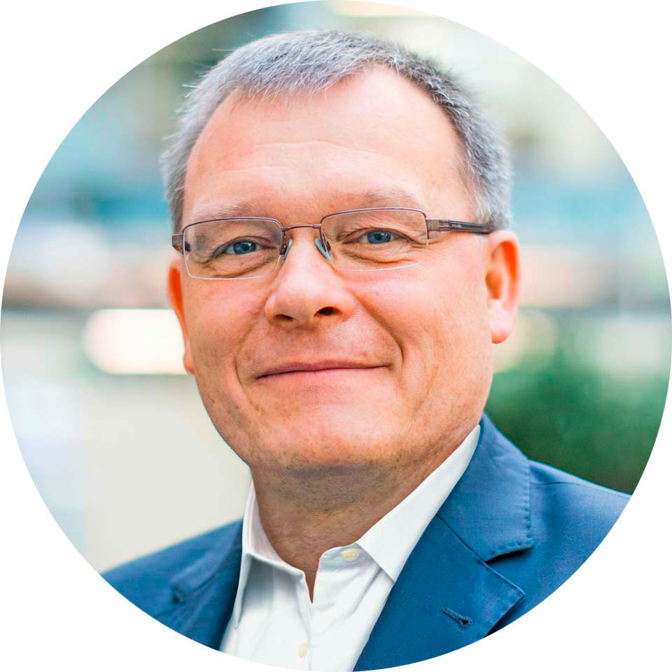 Porträt eines lächelnden Mannes mit Brille in Anzug, Mittleren Alters, freundlich blickend.