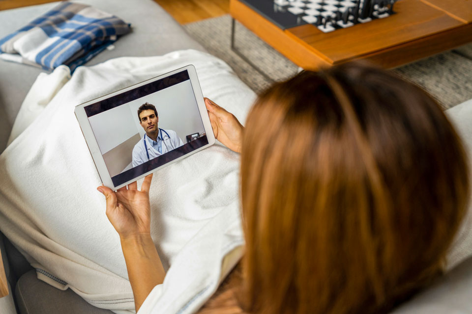 Frau hält Tablet mit dem Bild eines Arztes (Foto: andresr/iStock)