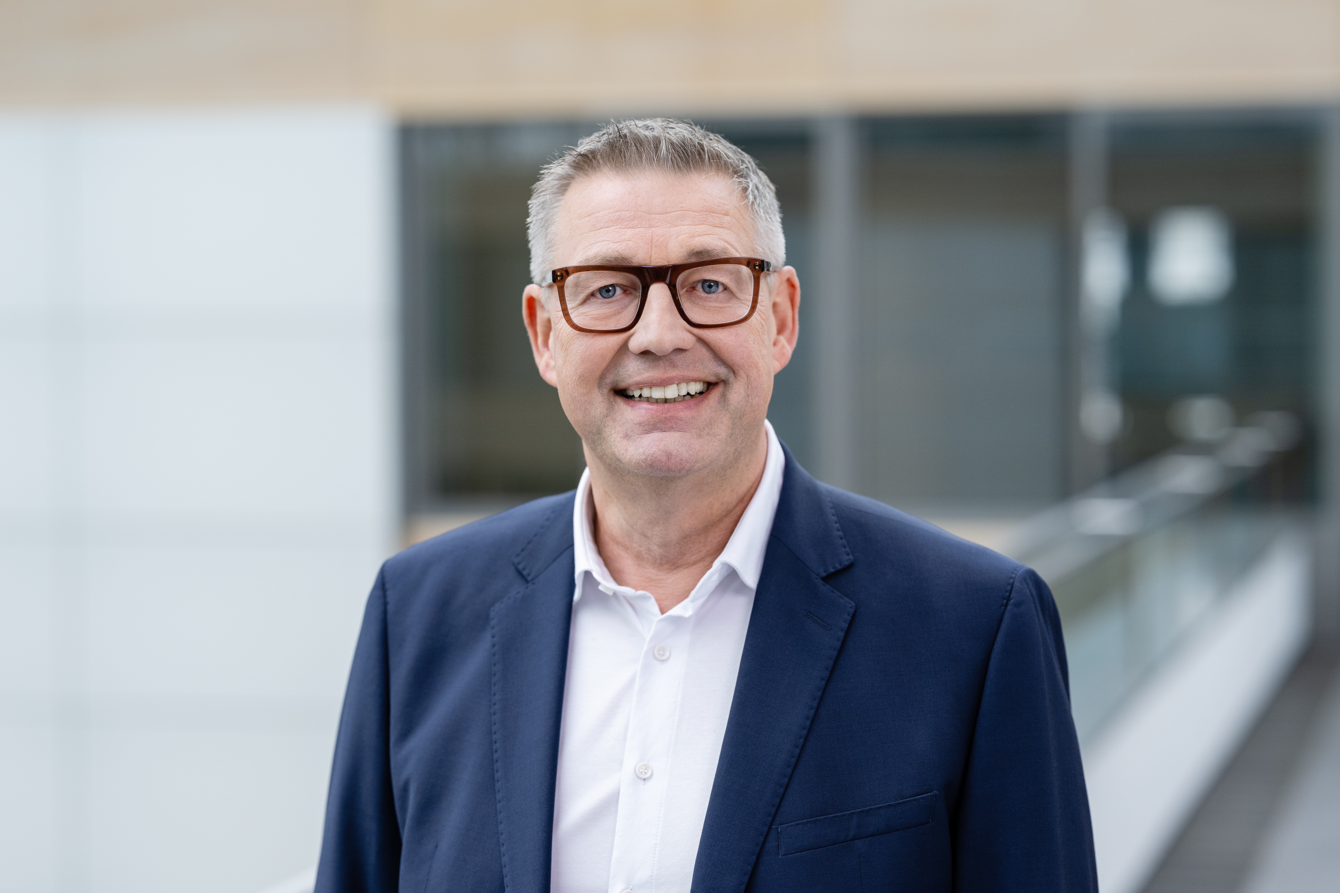 Portrait eines lächelnden Mannes im Anzug mit Brille