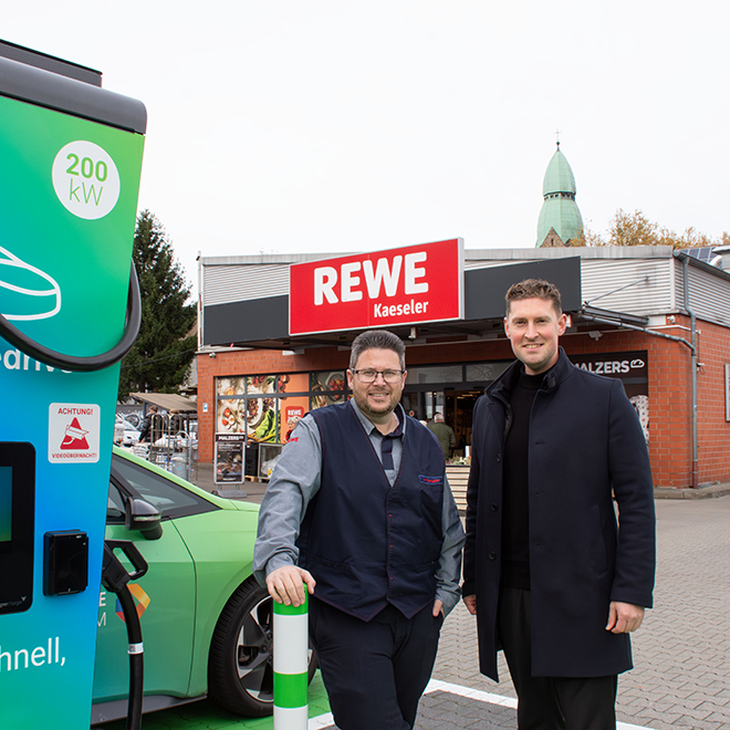 v.l. André Kaeseler und Jannis Bär an den neuen HPC-Ladestationen auf dem REWE-Parkplatz in Bochum-Gerthe