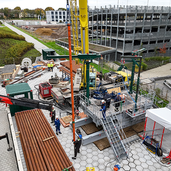 Bauarbeiter auf einer Baustelle mit Kränen und Rohrleitungen