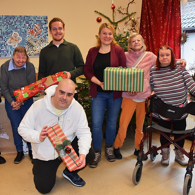 Gruppe mit Geschenken vor Weihnachtsbaum