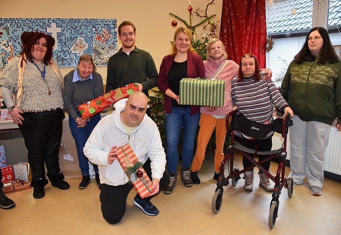 Gruppe von Menschen mit Weihnachtsgeschenken in Innenraum