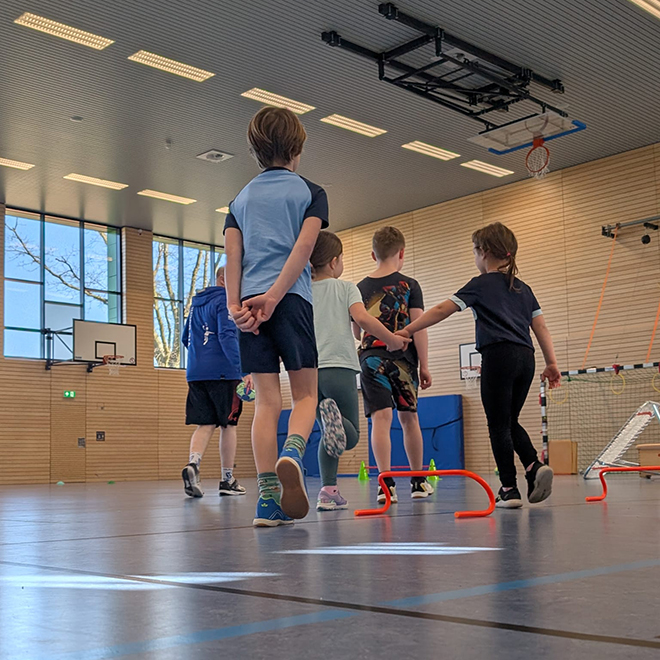 Kinder spielen Handball in einer Sporthalle