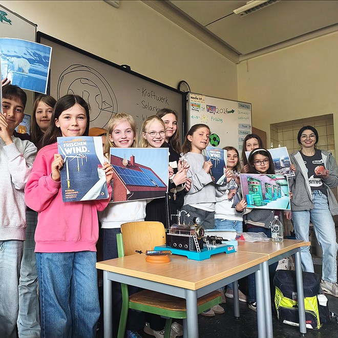 Schulkinder mit Bildern zu erneuerbaren Energien im Klassenzimmer