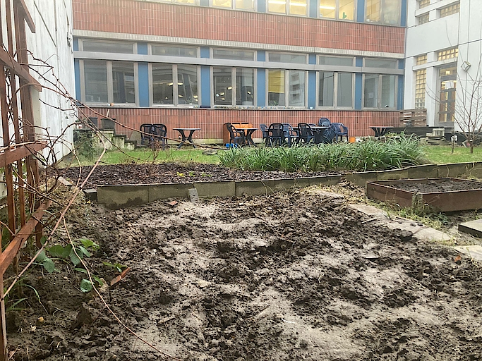 Innenhof mit Gartenbeeten und Sitzbereich vor einem Bürogebäude