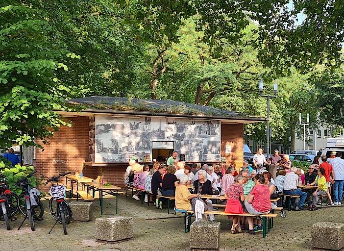 Menschen sitzen vor Kiosk bei Sommerfest in Bochum