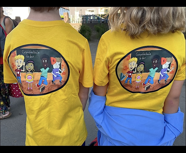 Rückansicht von zwei Kindern mit gelben Shirts und bunter Aufschrift