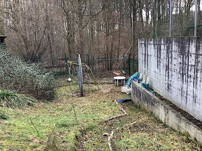 Verlassener Garten mit Spielgeräten und verwildertem Grün