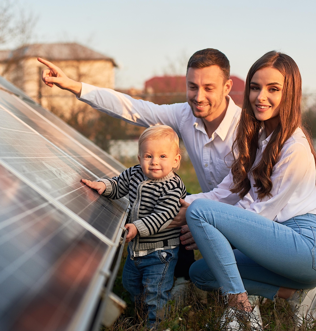 Familie betrachtet Solarzellen im Freien; Kind, Eltern zusammen neben Solarpanel.