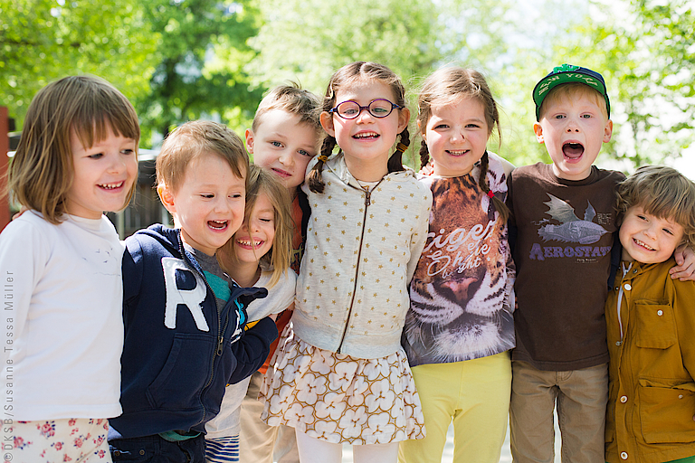 Glückliche Kinder stehen eng nebeneinander im Freien