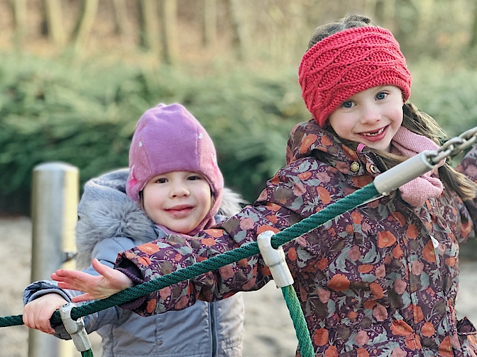 Zwei Kinder spielen draußen an Kletterseilen
