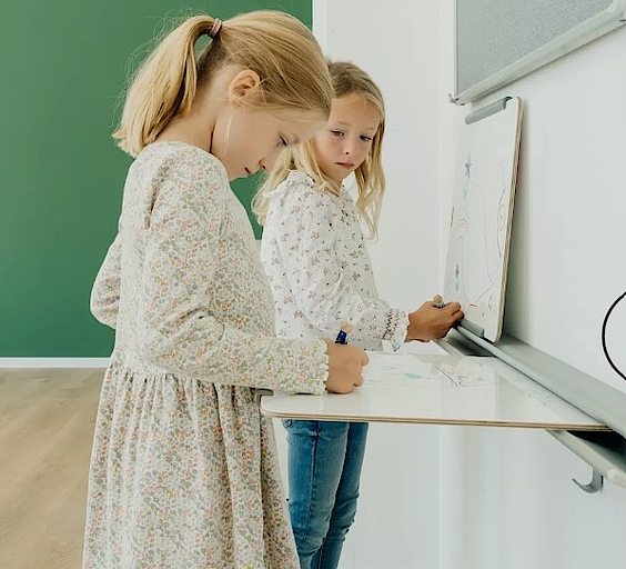 Zwei Mädchen zeichnen an einer Wandtafel