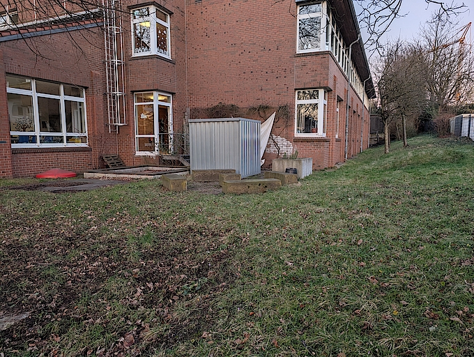 Metallcontainer vor rotem Backsteingebäude und Grasfläche in Bochum