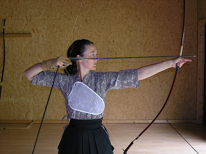 Frau beim traditionellen Bogenschießen mit Pfeil und Bogen