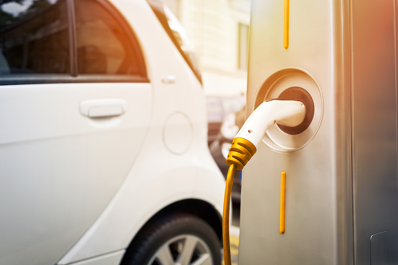 Elektroauto an Ladestation, der Ladestecker ist eingesteckt und der Ladevorgang läuft im urbanen Umfeld.