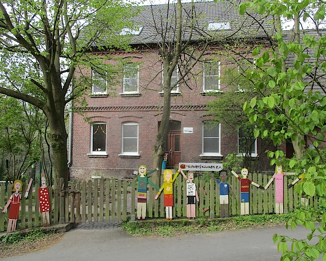 Holzfiguren vor einem Backsteinhaus in Bochum