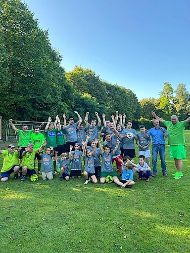 Gruppe von Kindern und Erwachsenen auf einem Fußballfeld