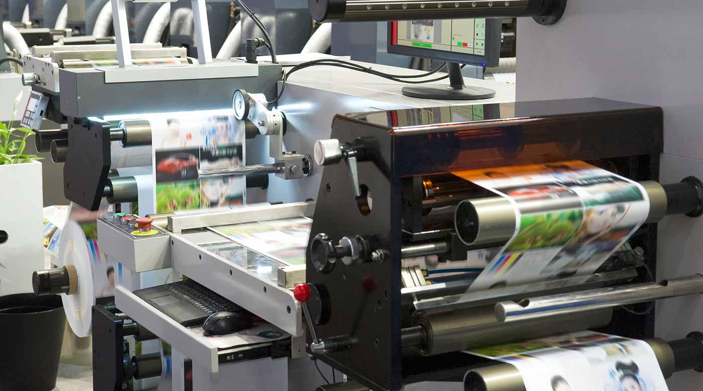 Moderne Druckmaschine druckt farbige Bilder auf Papierrollen in einer Druckerei.
