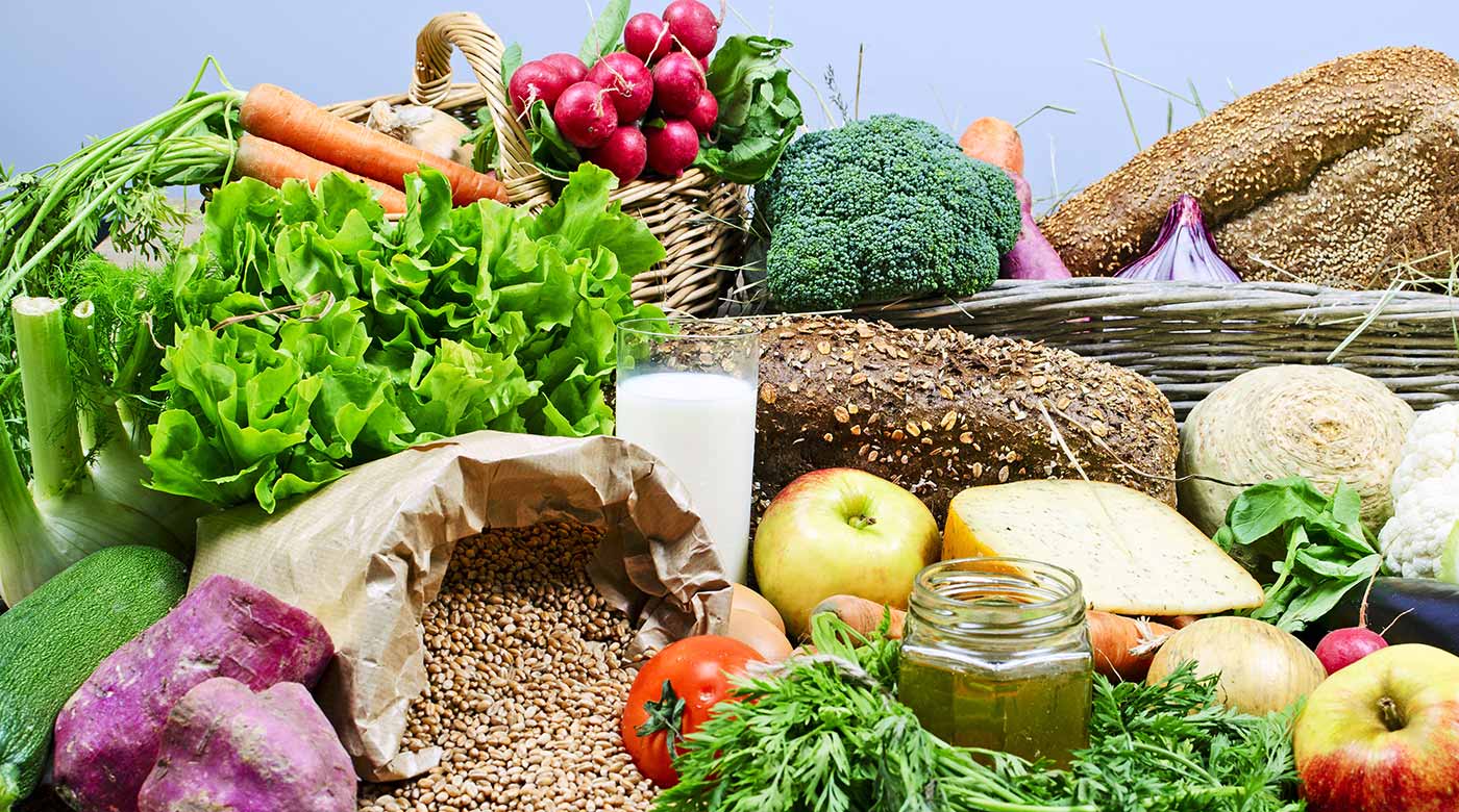 Vielfalt an frischem Gemüse, Obst, Körnern, Brot und Milch in Nahaufnahme.