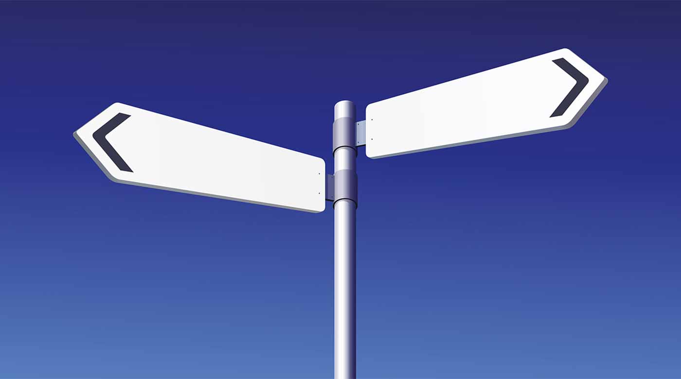 Zwei leere Wegweiser an einem Pfosten vor klarem, blauem Himmel.