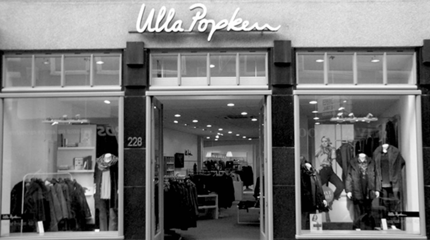 Eingang eines Ulla Popken Stores mit Schaufenster und ausgestellter Kleidung.