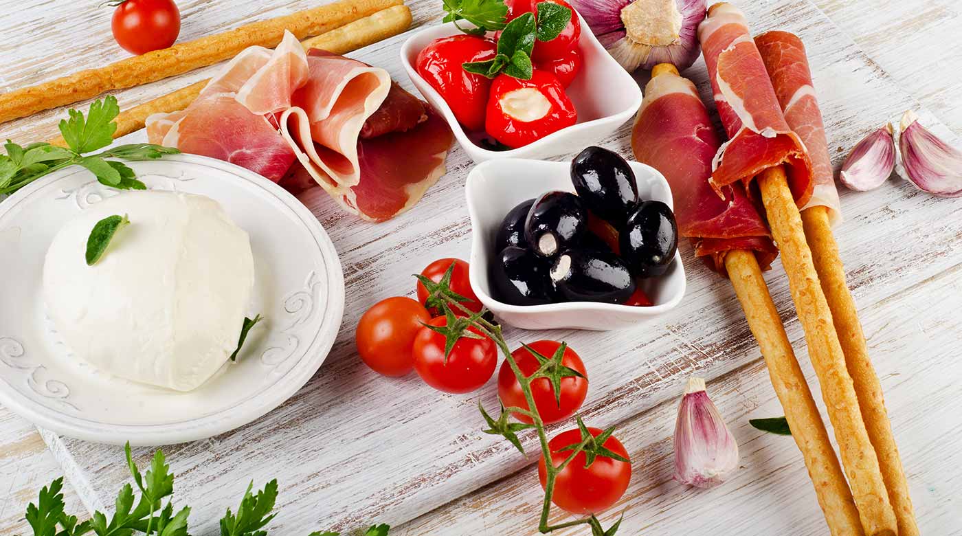 Italienische Antipasti mit Mozzarella, Prosciutto, Oliven, Tomaten und Knoblauch.