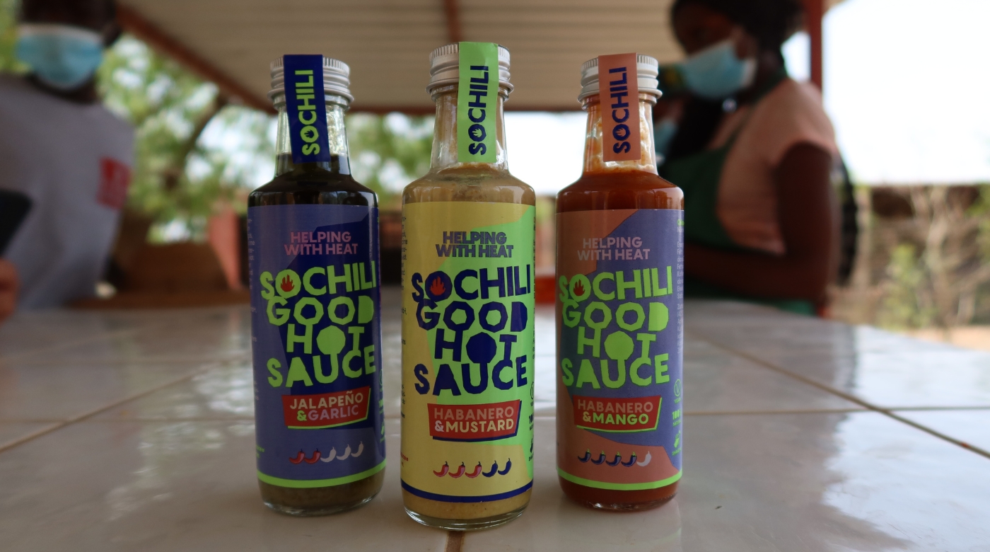 Geschenkbox mit Soßen, Avocado-Toast, Nachos, Cocktails und grün-weißem Tischtuch.