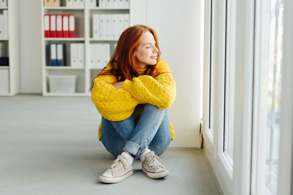 Foto einer jungen Frau, die entspannt im Büro auf dem Boden sitzt ( Foto: 2020 stockfour/Shutterstock)